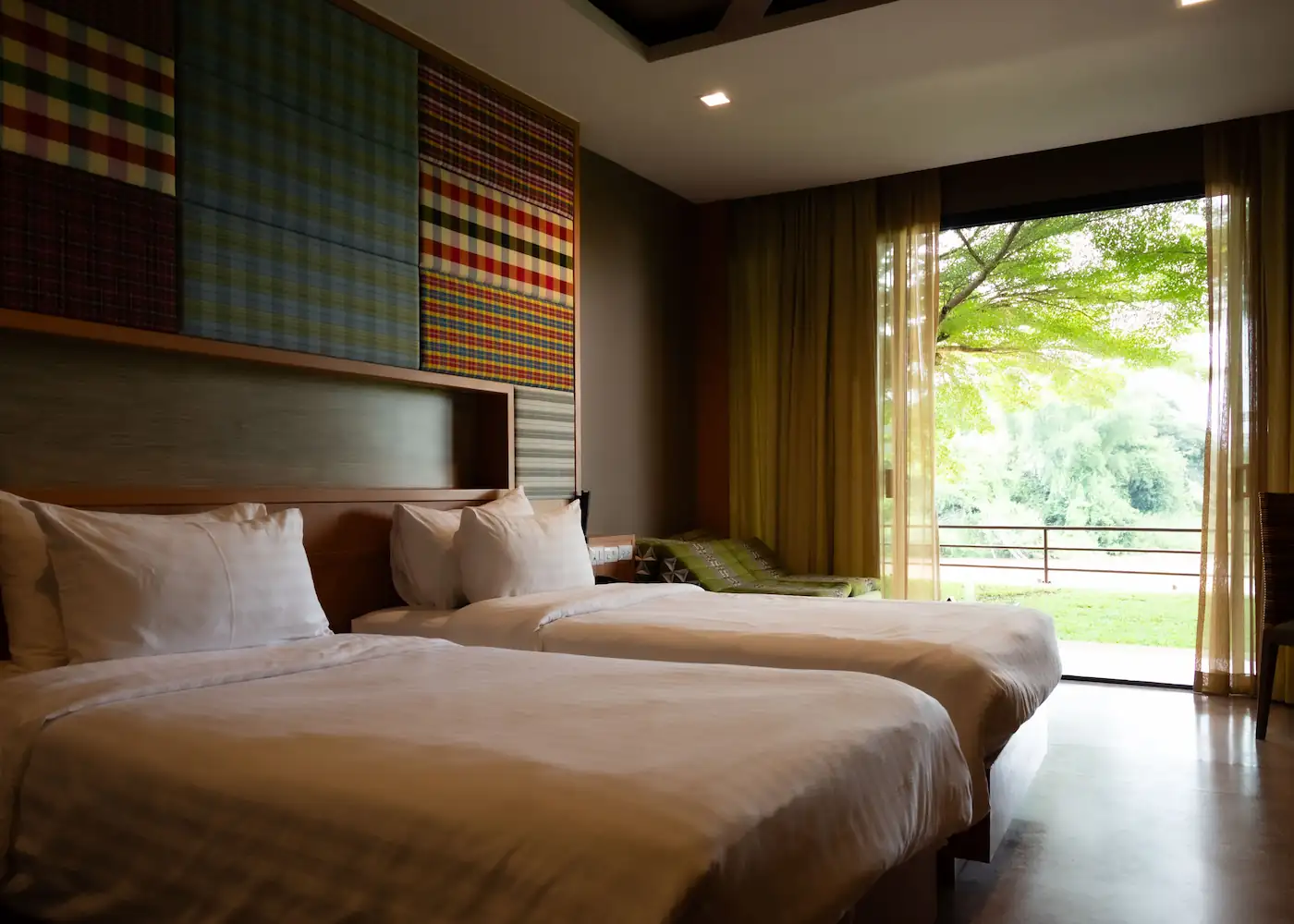 Bright and airy hotel room with two beds overlooking a lush garden.